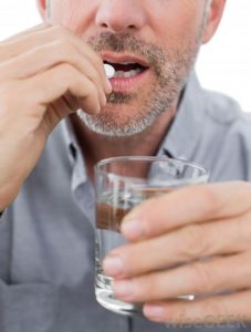 man-taking-pill-with-glass-of-water